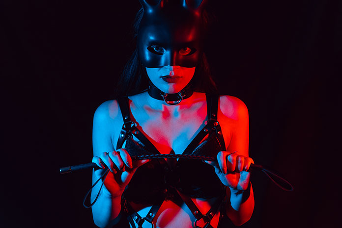 Frau mit BDSM Maske und Lederpeitsche